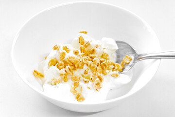 Greek yogurt with puffed wheat cereal covered with honey and spoon in a white bowl. Healthy and dietary food.