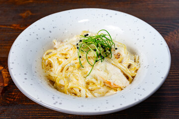 Creamy pasta dish garnished with herbs and spices on wooden table