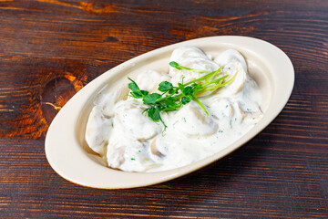 Delicious dish of creamy dumplings served on a wooden table