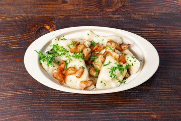 Delicious dumplings topped with crispy bacon on a wooden table