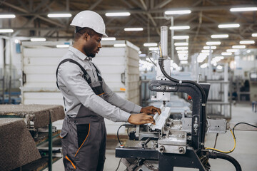 African American factory male worker operating machinery producing aluminum and pvc windows and doors