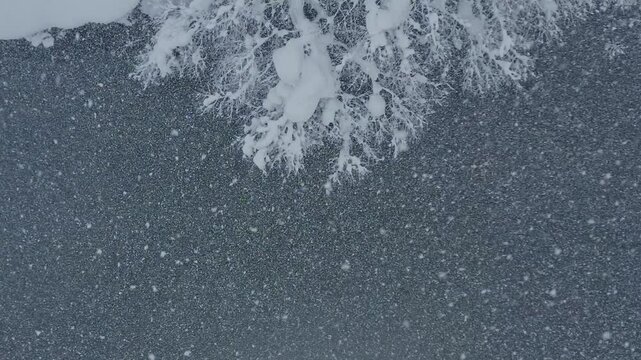 スーパースロー映像：ドローンで空撮した、大雪の日の川の上の風景