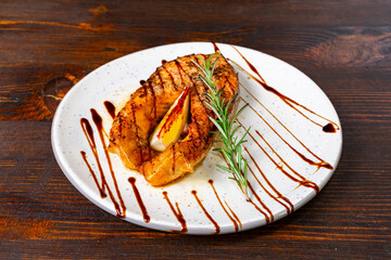 Grilled salmon fillet garnished with rosemary and sauce drizzle