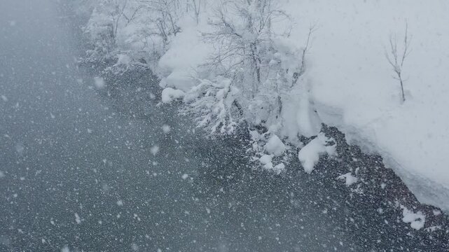 スーパースロー映像：ドローンで空撮した、大雪の日の川の上の風景