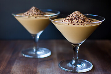 Delicious mousse served in elegant glass cups topped with chocolate shavings on a wooden table