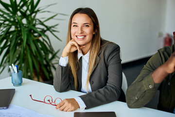 Smiling Businesswoman Sitting at Desk in Modern Office Environment
