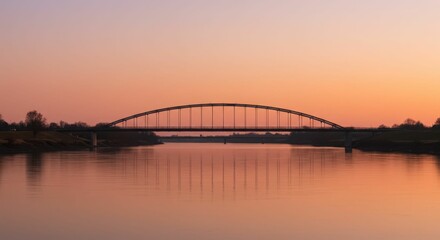 Fototapeta premium Sunset over tranquil river with arched bridge silhouette