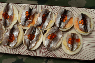 Bruschetta or toast with anchovies and red caviar on a plate. Banquet dish.