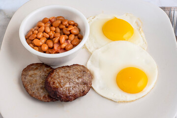 fried eggs with sausage patty  and baked beans