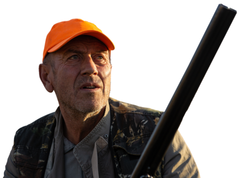 Mature man hunter with gun while walking on field.