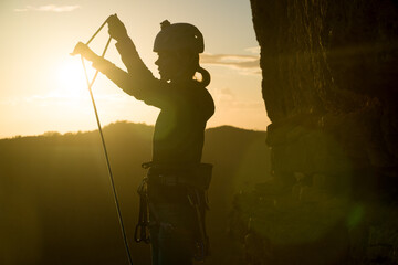 Young girl is preparing for training on the rocks sunset, in the mountains and puts a helmet on her head for safety to protect her health