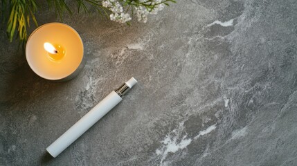 Vaping device on a polished stone surface next to a scented candle. Featuring simplicity and tranquility