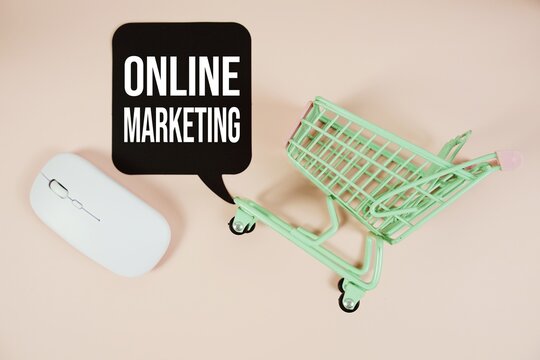 Online Marketing text on speech bubble with optical mouse and trolley shopping cart on pink background