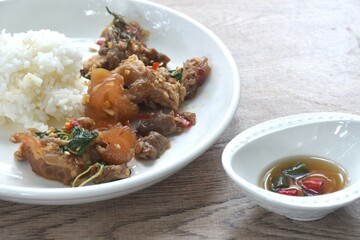 spicy stir fried slice braised beef meat and tendon with basil leaf and chili eat couple plain rice on plate  