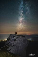 silhouette of a couple standing on a rock and watching perseid meteor shower