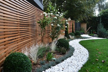 The garden of the house features flowers, trees, and green grass, surrounded by a wooden screen, as shown in this real photo