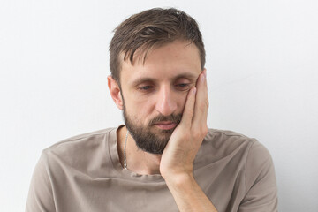 Fototapeta premium Man holding his cheek with a pained expression, indicating toothache, dental discomfort, or oral health issues, highlighting the need for dental care and treatment concept