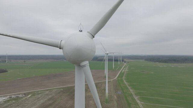 Orbiting shot of a wind turbine head slowly turning in a wind farm