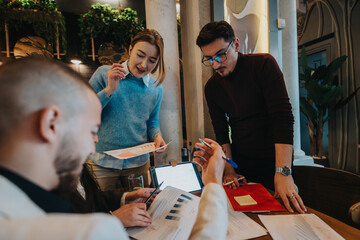 Three colleagues engaging in a brainstorming session, reviewing reports, and discussing strategies for a project in a stylish workspace, fostering teamwork, productivity, and innovation.