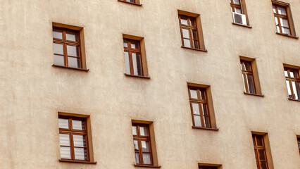 Pale orange wall facade of an old house with wooden brown windows