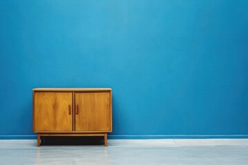 Minimalist living room setup with a wooden cabinet and sleek side table, placed in front of a sophisticated blue wall, offering a clean and modern aesthetic