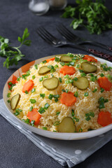Salad with chicken, cheese and carrots in white plate on gray surface