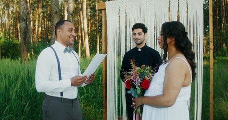 The groom reads the oath at the wedding ceremony, standing with the bride at the altar in front of...