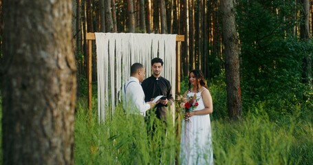 The groom reads the oath at the wedding ceremony, standing with the bride at the altar in front of...