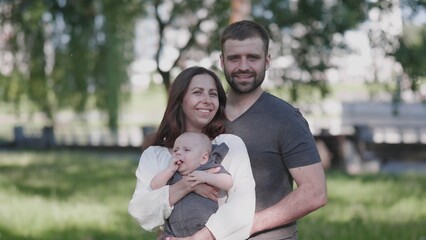 A loving family moment shows parents tenderly holding their adorable baby in a tranquil, beautiful...