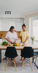 Mom and daughter cook in the kitchen slicing vegetables for salad