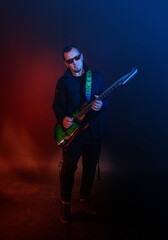 Fototapeta premium Musician rock guitarist plays electric guitar against red and blue background