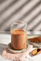 A protein shake with rich chocolate flavors and garnished with cocoa powder.