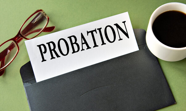 PROBATION - word on a white sheet of paper on a background of a black convers and a cup of coffee