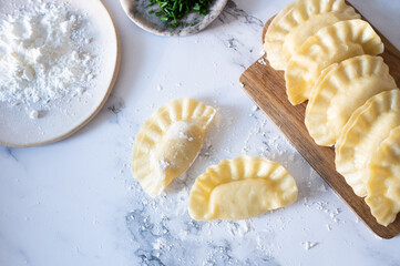 Raw dumplings coated in flour and lined up on a cutting board, ready for steaming or frying.