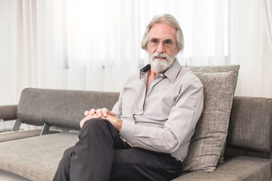 Happy 75-Year-Old Man with Gray Hair Relaxing on Couch, Smiling and Enjoying a Healthy, Balanced Life at Home