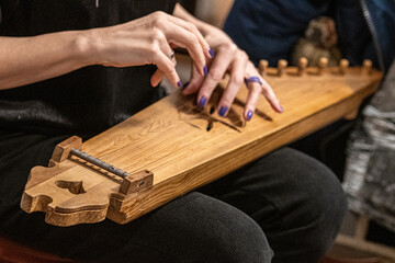 Fingers of a girl playing kankles, Lithuanian plucked string instrument belonging to the Baltic box zither family known as the Baltic psaltery, in Latvian kokles, Estonian kannel, Finnish kantele