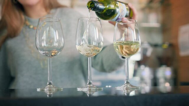 White wine poured in three wine glasses by female bartender