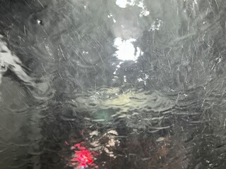 water is running down the front window of a car, view from the driver seat in automatic car wash. Rinse and reset concept
