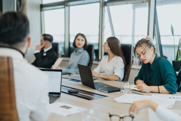 A diverse group of business people engaged in a meeting, brainstorming ideas and analyzing...