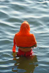 Indian young woman taking bath in sacred Gange river in Varanasi