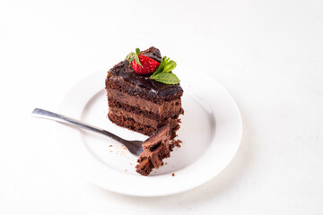 Dark chocolate cake slices, with chocolate cream and strawberry, on portioned plates, copy space