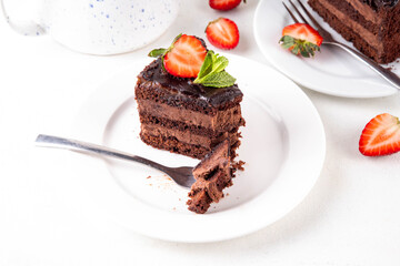 Dark chocolate cake slices, with chocolate cream and strawberry, on portioned plates, copy space