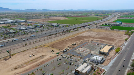 Aerial view of heavy traffic on highway next to construction site, green fields under near Phoenix...