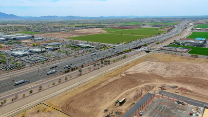 Highway traffic moves rapidly past fields, commercial properties in suburban setting on Phoenix Arizona