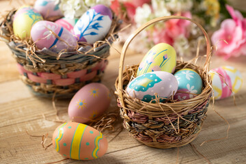 Decorated Easter eggs in a basket with flowers in background