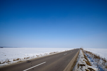 asphalt road on a snow-covered agricultural field