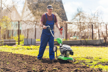 A man engaged in agriculture plows the soil with a cultivator for further planting of vegetables