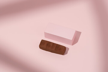 Pink mockup box and chocolate bar on pink isolated background with shadow. Concept of confectionery and sweets products, protein bars, advertising and packaging design.