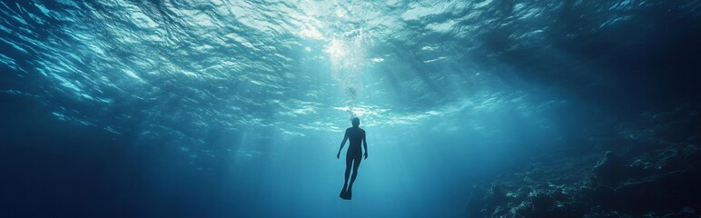 Fototapeta premium Diver exploring the deep blue ocean, sun rays penetrating the surface