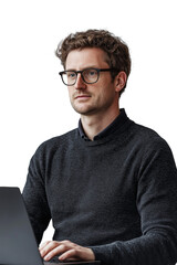 A focused young man wearing glasses and a black sweater is working on his laptop against a black background.